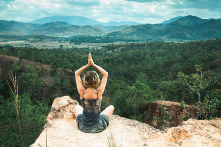 Young yoga woman meditates on a cliff top in a canyon.の写真素材