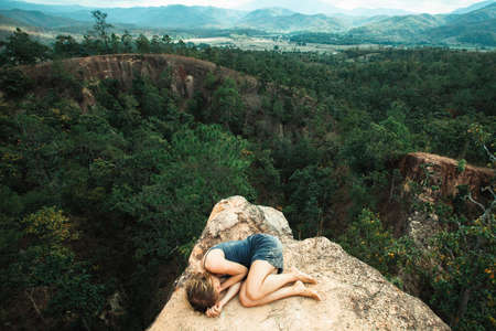 Young girl lying on top of the rock in the canyon. Thailand.の写真素材