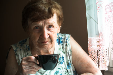 Portrait of an old woman drinking tea at home.の写真素材