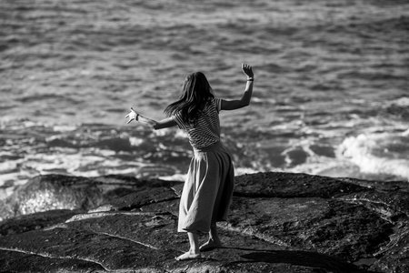 A young dance woman is engaged in choreography on the coast. Black and white photo.
