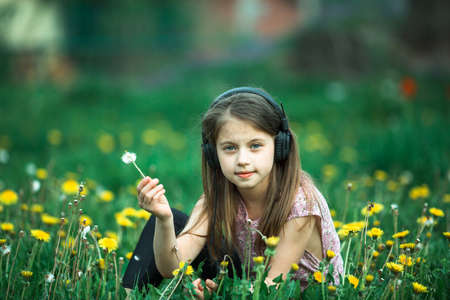 Little girl in headphones in the green field.の写真素材