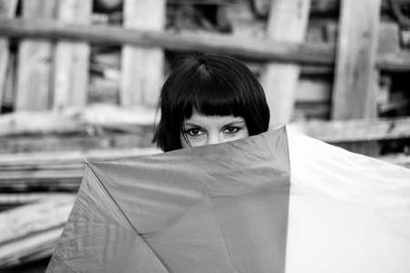 An woman peeping from behind the umbrella. Black and white photo.の写真素材