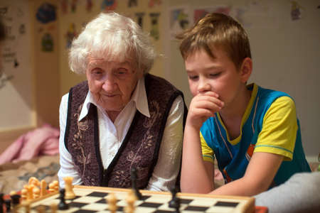 An old woman is playing chess with her little grandson.の写真素材