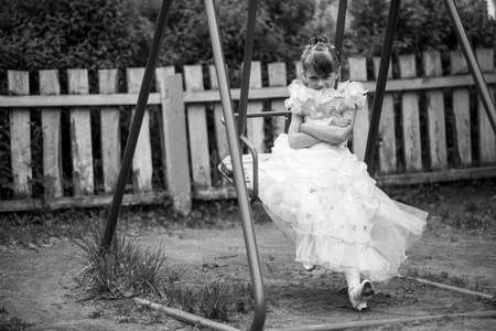 Little cute girl on the children's swing. Black and white photo.の写真素材