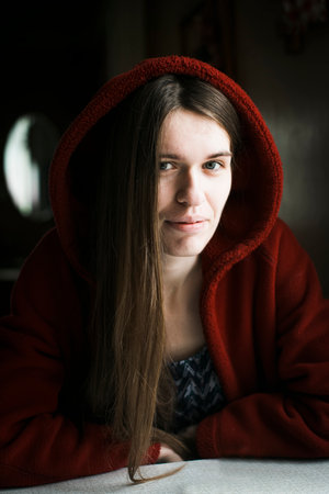 Young woman with long hair, in red, portrait in the house.の写真素材