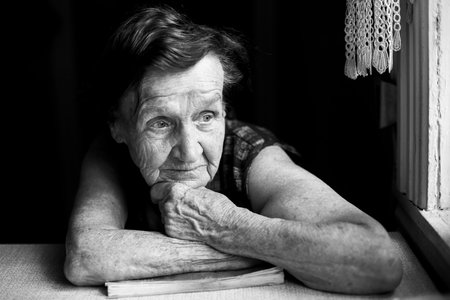 Portrait of pensioner woman sits in her house. Black and white photo.の写真素材