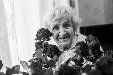 An senior woman with flowers in the her house. Black and white photo.の写真素材