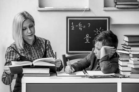 Youn student during homework with the help of a tutor. Black and white photo.
