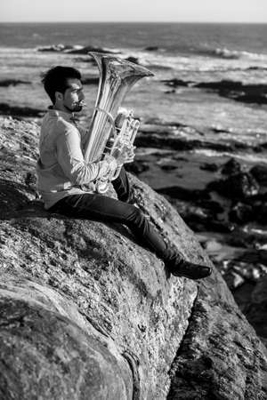A musician man with a tuba on the sea coast. Black and white photo.の写真素材
