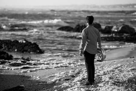 A musician man with a tuba on the seashore. Black and white photo.の写真素材