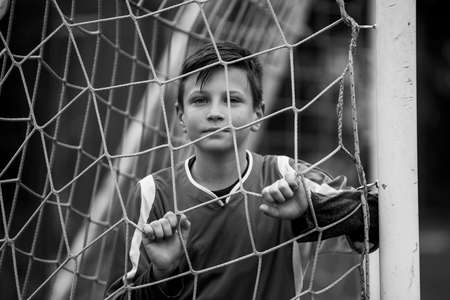 A boy football player near the gates of the stadium. Black and white portrait.の写真素材