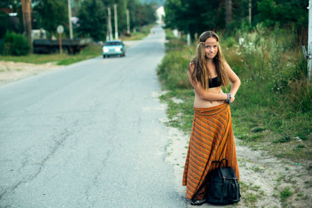 A hippie girl voting near the road. Hitchhiking trips.の写真素材