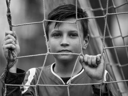 Little football player near the gates of the stadium, black and white portrait.の写真素材