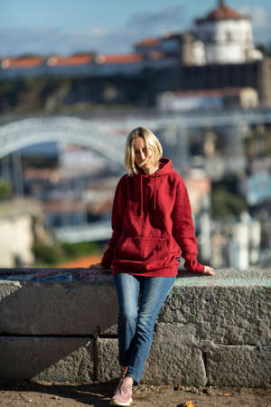 A woman in a hoodie in old town Porto, Portugal. Iron Bridge in the blur in the background.の写真素材
