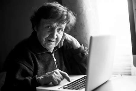 An old woman studying working on the computer in her home. Black and white photo.の写真素材