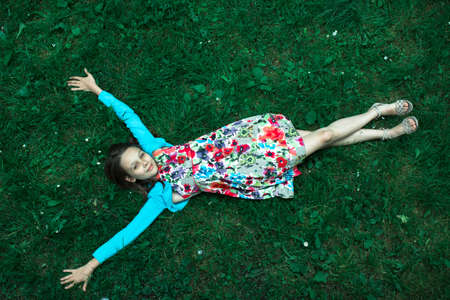 Girl lying on green grass, view from above.の写真素材