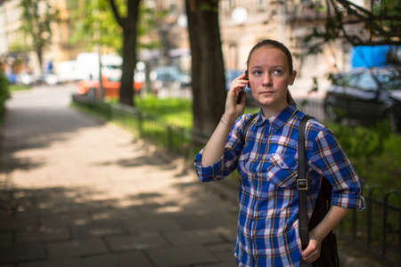 A teenage girl talking on her cell phone in a summer park.の写真素材