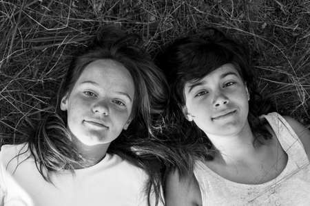 Portrait from above of the two girls lying on the grass. Black and white photo.の写真素材