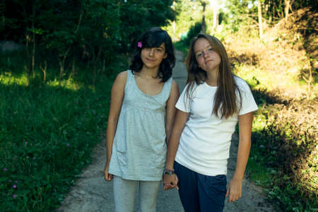 Two teenage sisters pose holding hands in the park.の写真素材