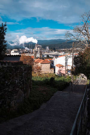 Smoke from the chimneys of a factory in an old town in Galicia, Spain.の写真素材