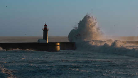 Lighthouse and huge wave on a beach Matosinhos at Atlantic ocean, Porto, Portugal.の写真素材
