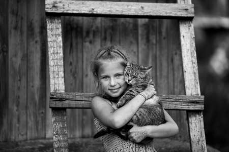 Little girl holds a cat in her hands. black and white photo.の写真素材