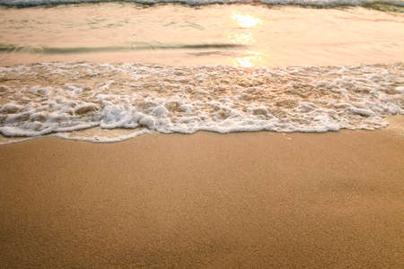 Texture of the sea beach sand with a soft lapping wave during sunset.の写真素材
