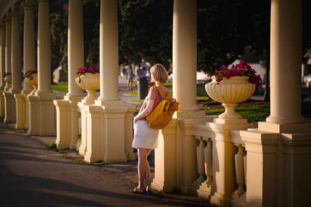 A woman with a yellow backpack is standing in a park area.の写真素材