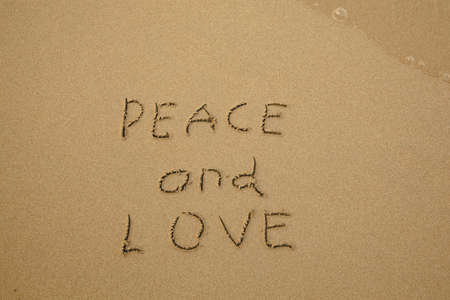 Peace and Love - handwritten on the soft beach sand.の写真素材