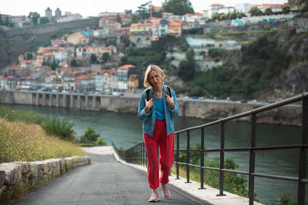 A woman tourist tired of climbing a mountain. In the background in a blur is the city of Porto, Portugal.の写真素材