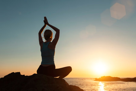 Yoga woman meditating on the ocean beach during a beautiful sunset.の写真素材