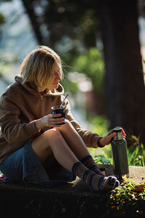 Cheerful woman in the park pours mate in a Mate cup.の写真素材