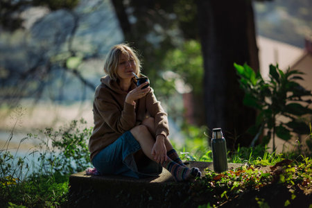 A woman drinks mate in the park from a Mate cup.