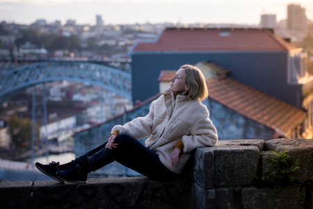 A female tourist rest on a masonry wall in Porto, Portugal.の写真素材