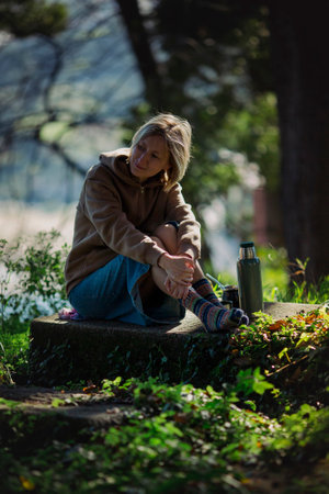 A woman sits in the park with a and a cup of Mate.の写真素材
