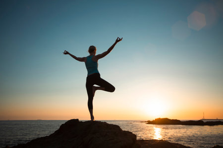 A woman doing yoga on the beach during sunset.の写真素材