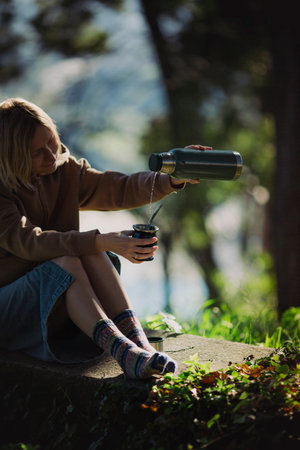 A female in the park delights in pouring mate from a into a Mate cup.の写真素材