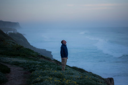 A man stands on the Atlantic coast against the background of the morning surf.