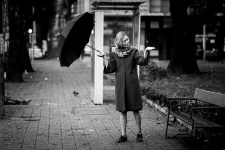 A woman opens her umbrella outside checking for rain. black and white photo.の写真素材