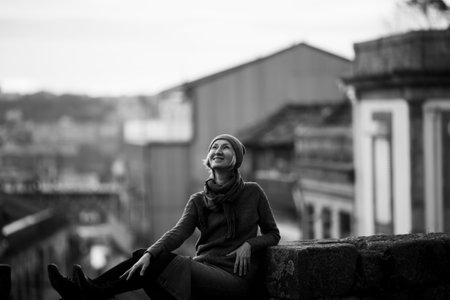 A woman relaxing by an ancient stone wall in Porto, Portugal. black and white photograph.の写真素材
