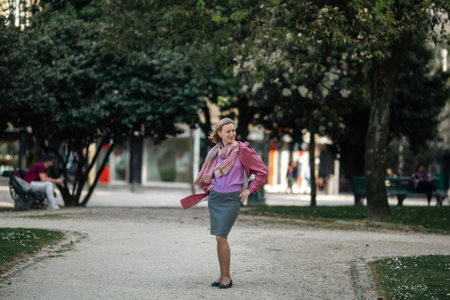 A woman in a raincoat is waiting for a date in the square.の写真素材