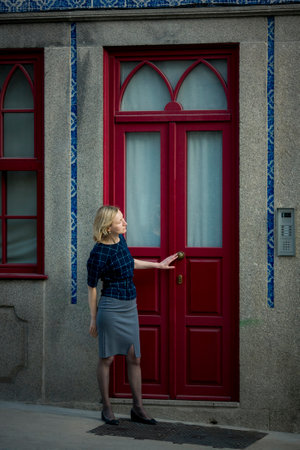 A woman knocks on a tall traditional door at a house in Porto, Portugal.の写真素材