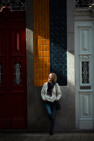 A woman stands in a beam of natural light waiting at the door of a traditional Portuguese house.の写真素材