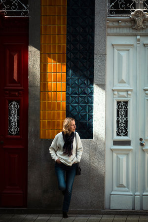 A woman waits standing outside a traditional Portuguese town house.の写真素材