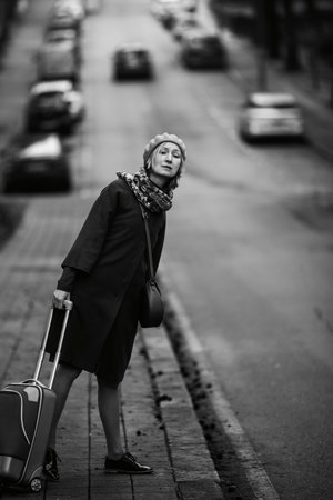 On the side of the road, a woman with a suitcase votes. Black and white photo.の写真素材