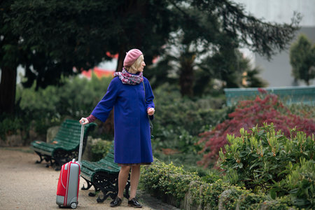 Walking down the street is a woman with a red suitcase.の写真素材