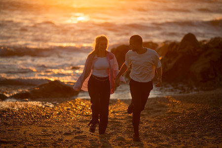 A young couple enjoying a golden sunset on the beach.の写真素材