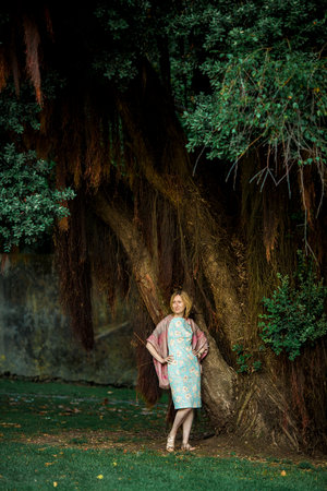 Portrait of female standing by large tree in park.の写真素材