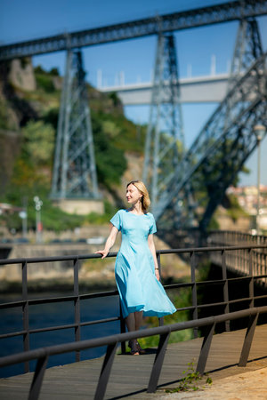 On a city promenade stands a woman in a blue dress.の写真素材