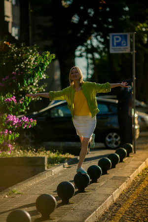 A happy woman on a city street at sunset.の写真素材
